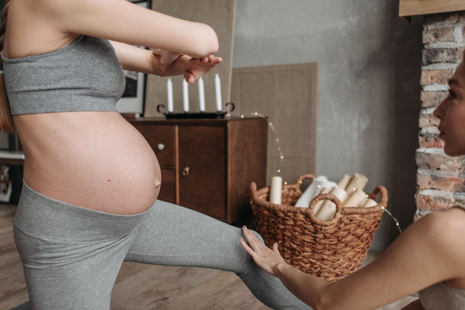 A pregnant woman in a gently supported yoga posture, assisted by an instructor